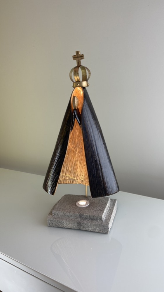 Escultura luminária de Nossa Senhora Aparecida em folha de bananeira sobre base de pedra
